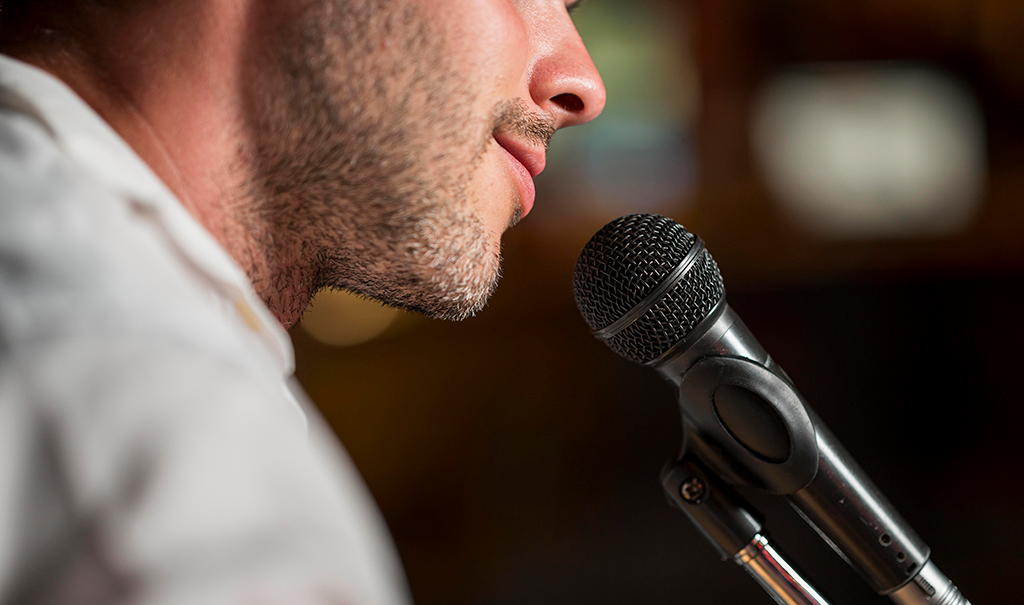 Homem diante de um microfone para ilustrar uma boa oratória.