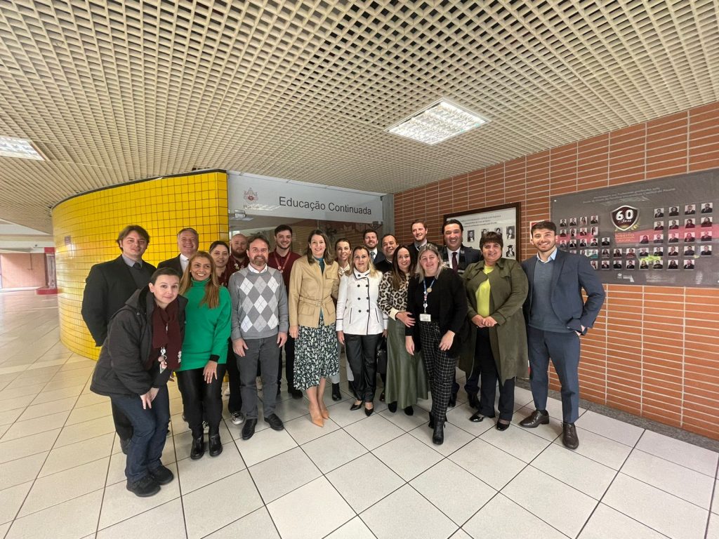 Cooredenadores dos cursos de especialização posando para uma foto em frente à secretaria de Educação Continuada PUCPR.